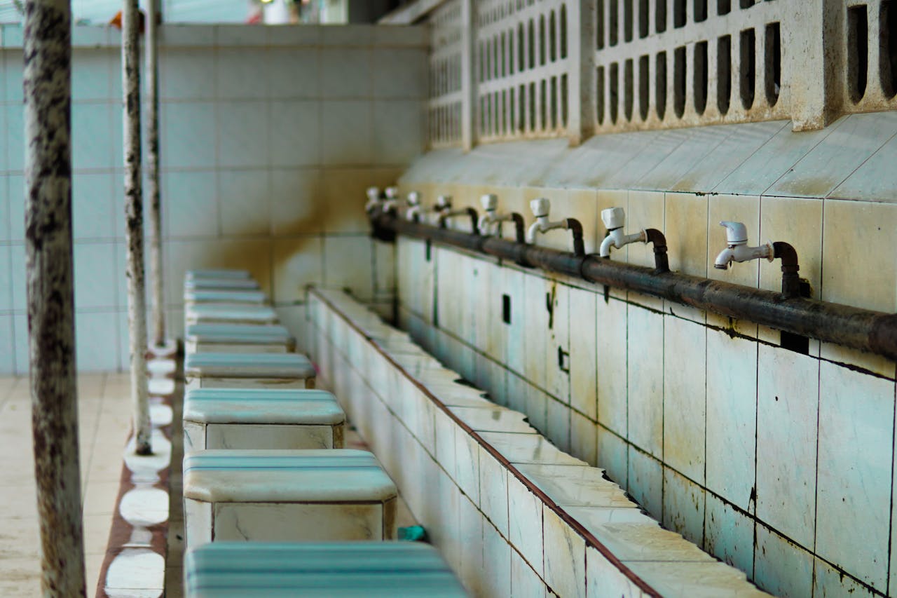 An empty tiled wash area featuring faucets and benches, highlighting rustic details and serene atmosphere.